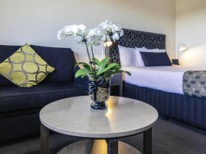 a room with a couch and a table with a vase with flowers at Mercure Albury in Albury
