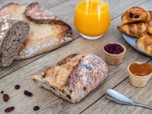 a wooden table topped with bread and orange juice and orange juice at ibis Styles Sceaux Paris Sud in Sceaux