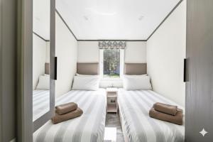 twee bedden in een kleine kamer met een raam bij Luxury Lodge 