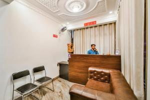 a man standing behind a bar with a leather couch at Hotel O Tirupati Residency Kota Airport in Kota