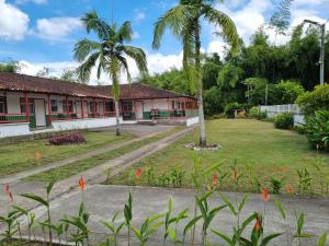 a building with palm trees in front of a yard at Hotel campestre La Floresta in Armenia