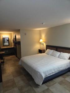 a bedroom with a large white bed and a table at Twin Lakes Inn & RV Park in Stigler