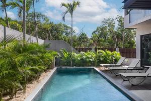 图卢姆6BR Villa at Premium Location 24 h Security的后院的游泳池,游泳池内摆放着椅子和棕榈树