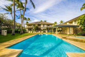 a swimming pool in front of a house with palm trees at 6BR Poipu Kai Oceanfront Retreat Steps to 3 Beaches in Koloa