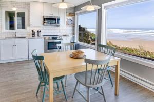 Ocean Front with Beautiful Views! The Beach House-Seal Rock في Bayshore: مطبخ مع طاولة وكراسي مطلة على الشاطئ