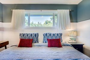 Ocean Front with Beautiful Views! The Beach House-Seal Rock في Bayshore: غرفة نوم بها سرير مع وسائد حمراء ونافذة