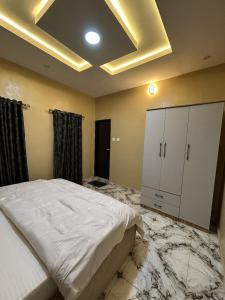 Schlafzimmer mit einem großen Bett und Marmorböden in der Unterkunft Radores Apartments in Ayobo