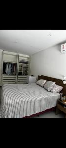 a bedroom with a large bed with a striped comforter at Apartamento aconchegante e moderno próximo do aeroporto e ao centro in Porto Seguro