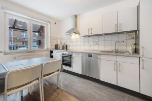 a kitchen with white cabinets and a table with chairs at Ferienhaus Heide in Bad Fallingbostel