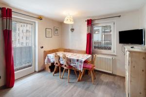 a dining room with a table and a television at Appartamento Giulia in Canazei
