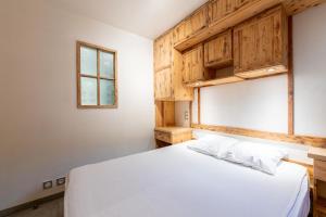 une chambre avec un lit blanc et une fenêtre dans l'établissement Appartement - Lanslevillard, à Val Cenis