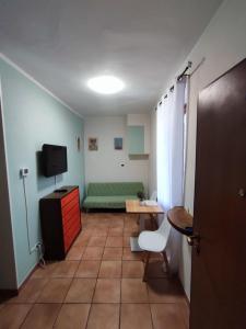 Una sala de estar con un sofá verde y un televisor. en Appartamento vicino alla madonnina di tortona, en Tortona