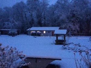 une maison avec de la neige devant elle dans l'établissement Bungalow am Haussee, à Himmelpfort