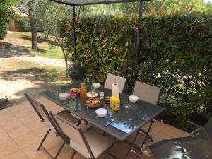 Una mesa con comida, sillas y una sombrilla. en Gite les Mazets du Rouret, en Saint-Christol-lès-Alès