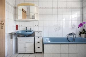 ein Badezimmer mit einem Waschbecken und einer blauen Badewanne in der Unterkunft Ferienwohnung Winzenburg in Rehburg-Loccum + 20 Fotos