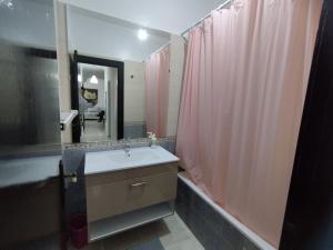 a bathroom with a sink and a pink shower curtain at heartofrabat in Rabat