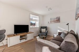 a living room with a couch and a flat screen tv at Ferienhaus Waterkant mit Hund in Klanxbüll