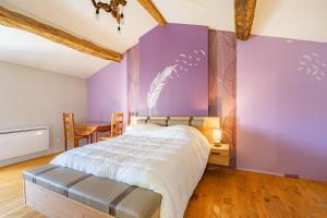 een slaapkamer met een bed met paarse muren en een tafel bij Maison à Cozes in Cozes