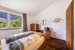 a bedroom with two beds and a desk and a window at Angerblick Apartment in Appiano sulla Strada del Vino