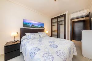 a bedroom with a bed with a blue and white comforter at Brillant in Cala Ratjada