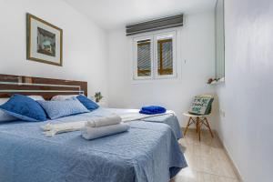 a bedroom with a bed with blue sheets and a window at Mar Y Sol in Caleta De Fuste