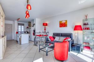 Una sala de estar con un sofá rojo y una cocina. en Petite maison Aigues Mortes, en Aigues-Mortes