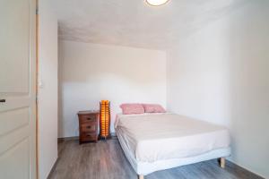 a bedroom with a white bed and a wooden dresser at Gîte indépendant l'Orchidée in Lespignan