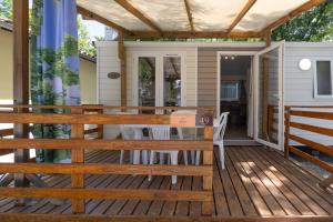 LavilledieuにあるLes Rives d’Auzon Confort 4 persのデッキにテーブルと椅子が置かれたポーチ