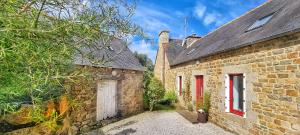 ein altes Steingebäude mit einer weißen Tür und roten Fenstern in der Unterkunft Villa Kermohic - en front de mer in Pleubian