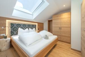 a bedroom with a white bed with a skylight at Furnerhof Apt Stearnzauber in Collepietra