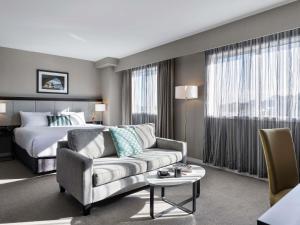 a hotel room with a couch and a bed at The Sebel Auckland Manukau in Auckland +55 photos