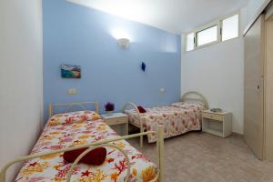 deux lits dans une chambre aux murs bleus dans l'établissement La Casa Al Mare, à Castelsardo