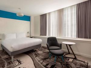 a bedroom with a bed and a chair and a table at ibis Styles Glasgow Central in Glasgow