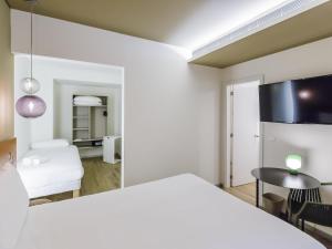 リスボンにあるIbis Styles Lisboa Centro Marquês de Pombalの白いベッドとテーブルと椅子のある部屋