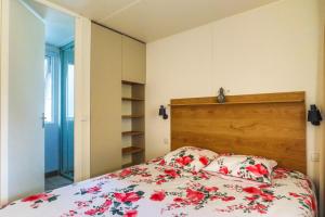 a bedroom with a bed with red flowers on it at Mobilhome Biscarrosse 6 personnes in Biscarrosse