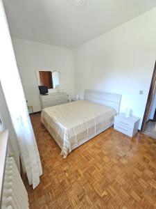 a white bedroom with a bed and a wooden floor at Riverside San Pellegrino in San Pellegrino Terme