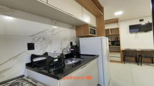Una cocina con fregadero y refrigerador blanco. en Studio em Bauru no Centro da Cidade, en Bauru
