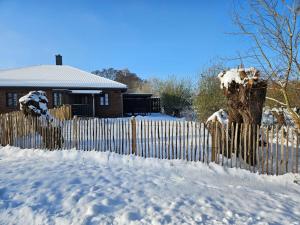 une clôture recouverte de neige devant une maison dans l'établissement Ferienwohnung - Wolkow, à Wolkow