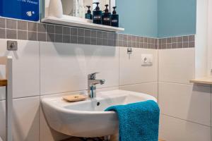 La salle de bains est pourvue d'un lavabo et d'une serviette bleue. dans l'établissement Ferienwohnung - Wolkow, à Wolkow 19 autres photos