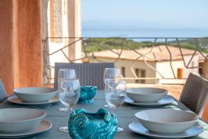 une table avec des assiettes et des verres à vin sur un balcon dans l'établissement La Pavoncella, à Santa Teresa Gallura