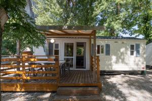 a small white tiny house with a wooden deck at Les Rives d’Auzon Mobil-home 6 pers in Lavilledieu