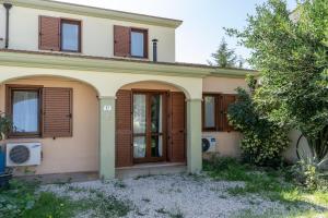 een huis met houten luiken en een boom bij Villa Orchidea in Masainas