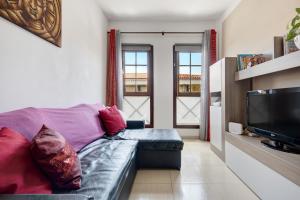 un salon avec un canapé violet et une télévision dans l'établissement Apartamento Elena, à Buenavista del Norte