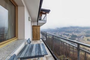 a balcony with a wooden bench and a view at Apartment Latemar Casa Alma in Tesero