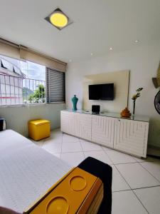 a bedroom with a bed and a flat screen tv at 12F- Pe na Areia do Tombo-2 Quartos, Ar Cond, 2w, 1 vaga e Roupas de Cama in Guarujá