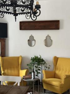a living room with yellow chairs and a chandelier at Podere Casa Rossa a Pienza in Pienza