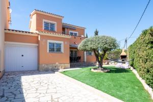a house with a green lawn in front of it at Villa Alpamar in Les tres Cales