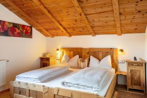 two beds in a bedroom with wooden ceilings at Malsötscherhof Apt C in Villandro
