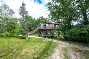 a tree house with a deck in the woods at La cabane de Gardelac in Saint-Rémy