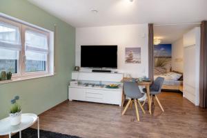 un salon avec une télévision, une table et des chaises dans l'établissement Ferienwohnung mit eigenem Eingang, à Deggenhausertal